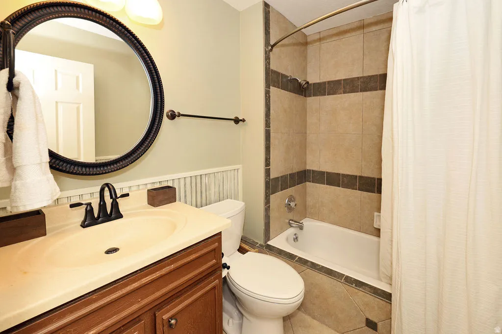 2nd story Full bathroom featuring a single vanity with a cream-toned countertop, dark bronze fixtures, beadboard wainscoting, and a tiled shower-bathtub combination