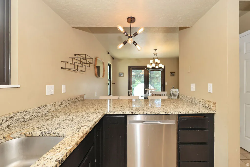 Kitchen featuring granite-look countertops, dark wood-finish cabinetry, and a stainless steel dishwasher
