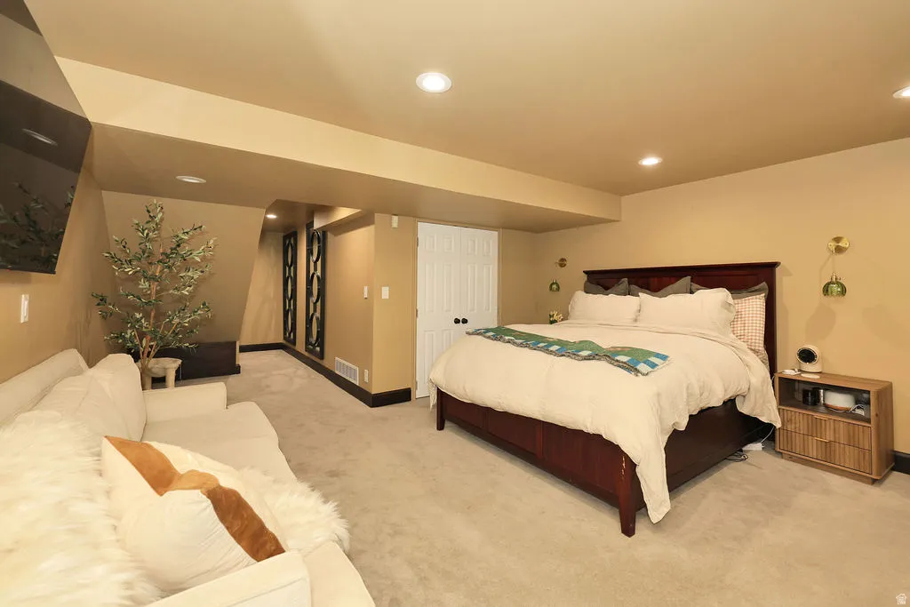basement family room currently being used as primary bedroom. Carpeted bedroom area featuring recessed lighting, a built-in entertainment niche, and a contrasting dark baseboard trim