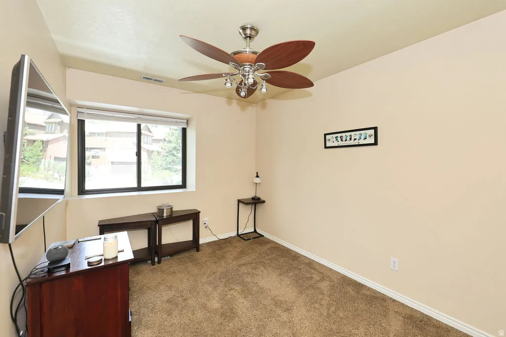 second floor bedroom (2 of 3 upper ) Window-equipped room featuring light-toned walls, a textured carpet, a ceiling fan with integrated lighting, and white baseboards