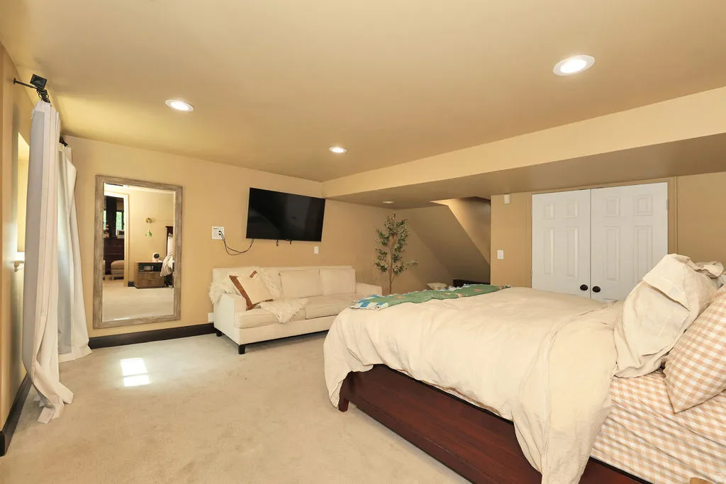 basement family room currently being used as primary bedroom.Carpeted room featuring recessed lighting, a built-in closet with bi-fold doors, and a wood-finish bed frame