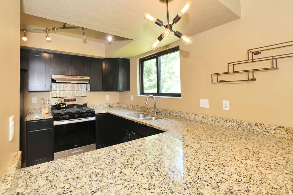 Kitchen featuring dark wood-finish cabinetry and light-toned, speckled countertops