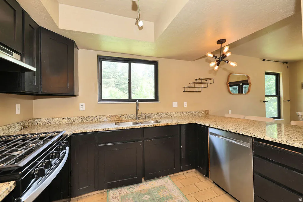 Kitchen featuring dark wood cabinetry, light speckled countertops, stainless steel appliances, and a gas range