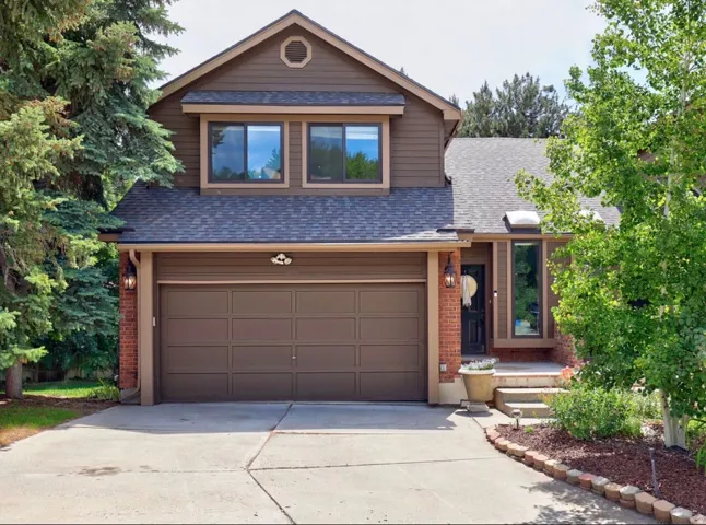 Two-story residence featuring a brown siding and brick exterior with a two-car garage