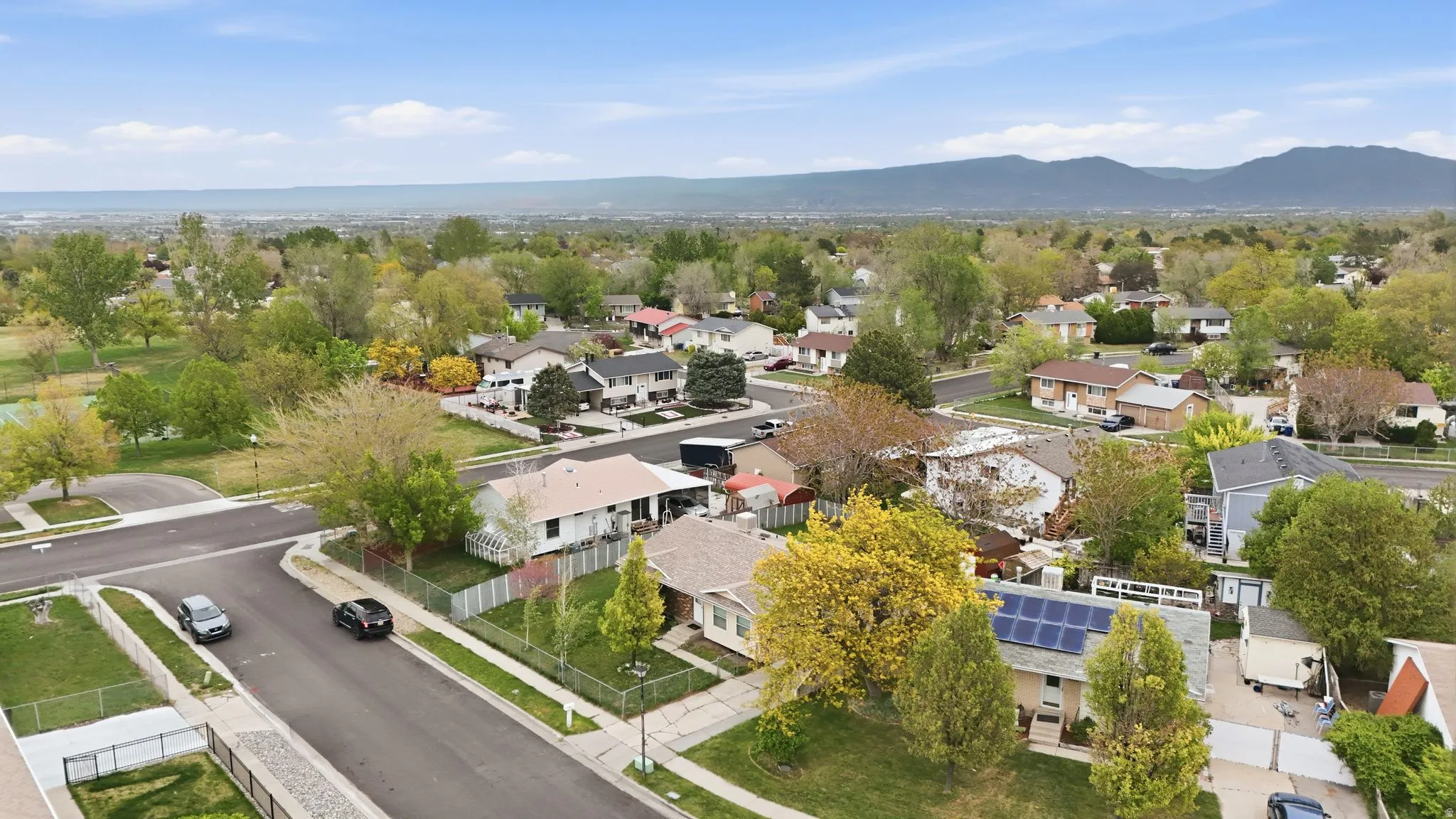 Residential neighborhood featuring a mix of mature trees and established homes, with distant mountains providing a scenic backdrop