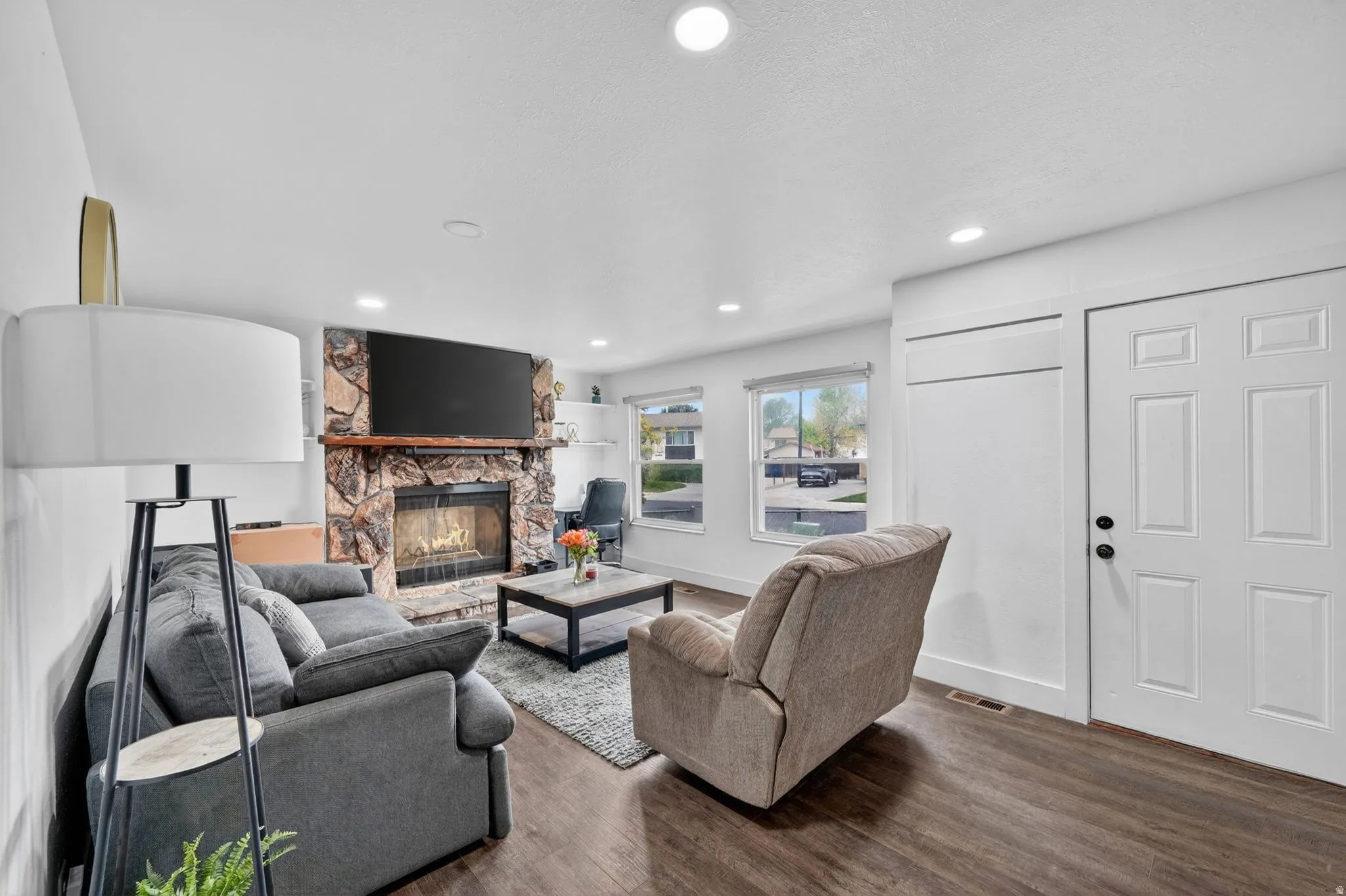 Living area featuring a stone fireplace with a wood mantle, recessed lighting, and wood-finish flooring