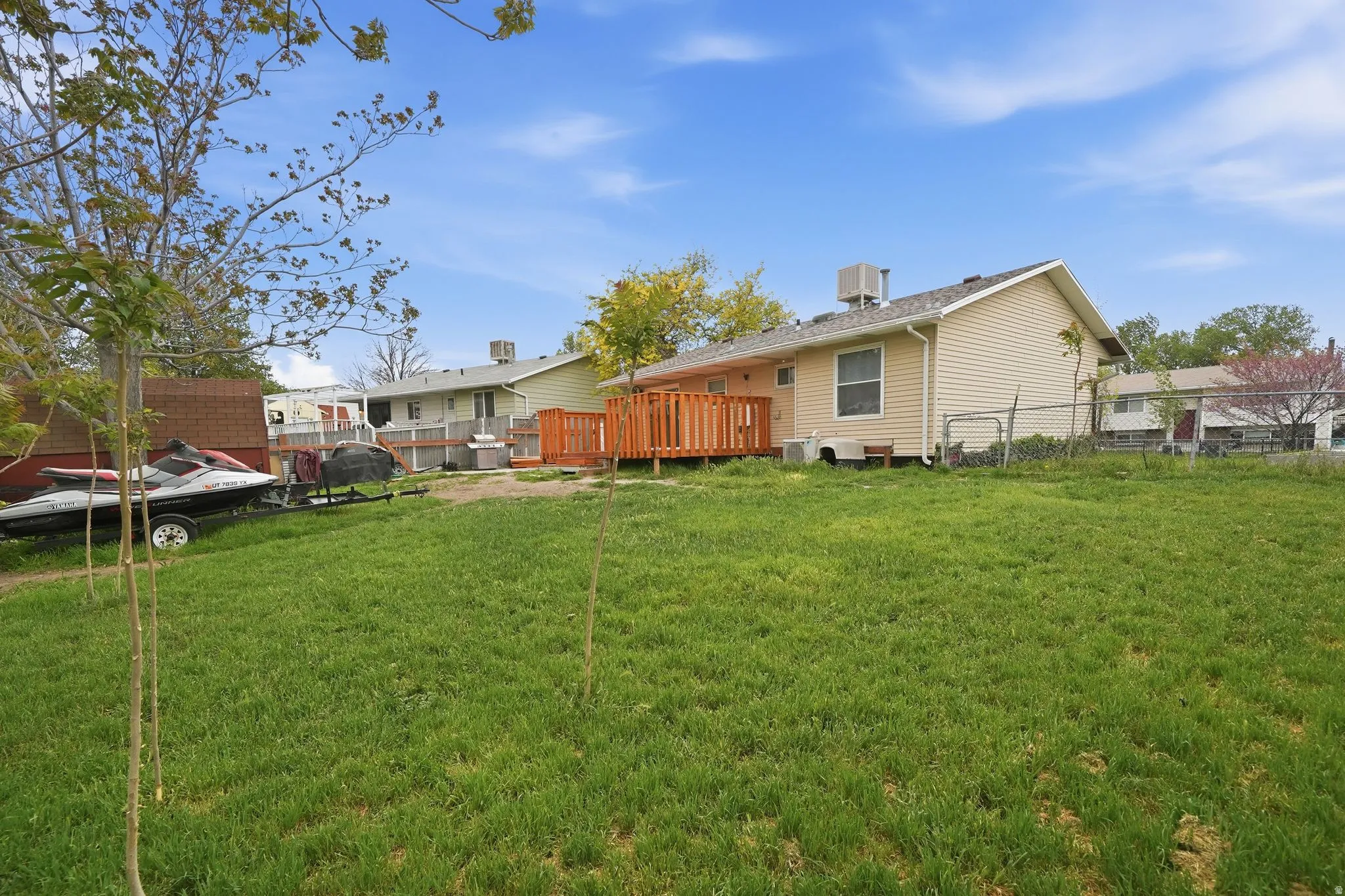 Expansive grassy yard with a multi-level wood deck and beige siding on the property