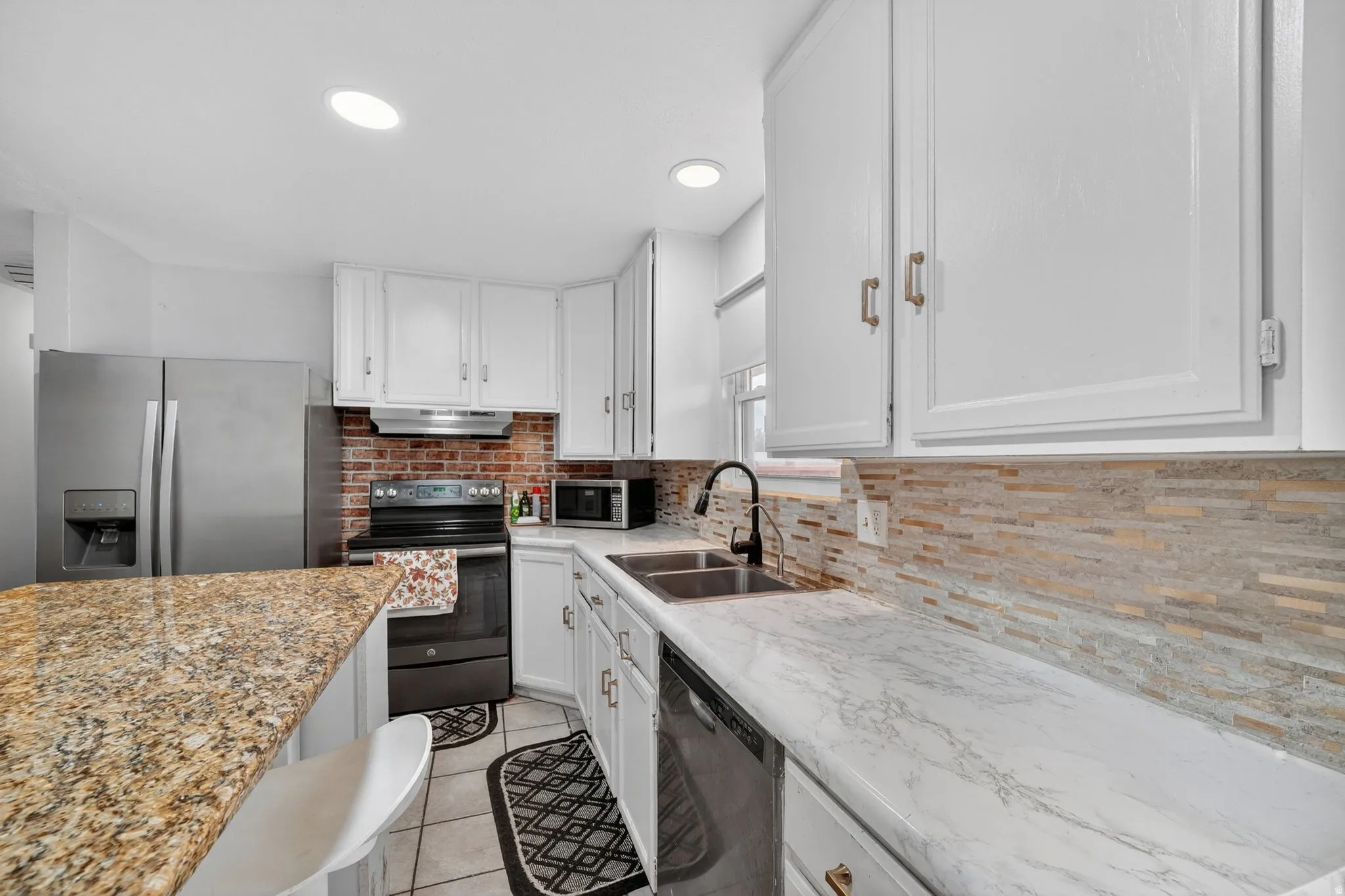 Kitchen featuring white cabinetry, a stainless steel refrigerator, black range, and a dual-basin sink with a matte black faucet