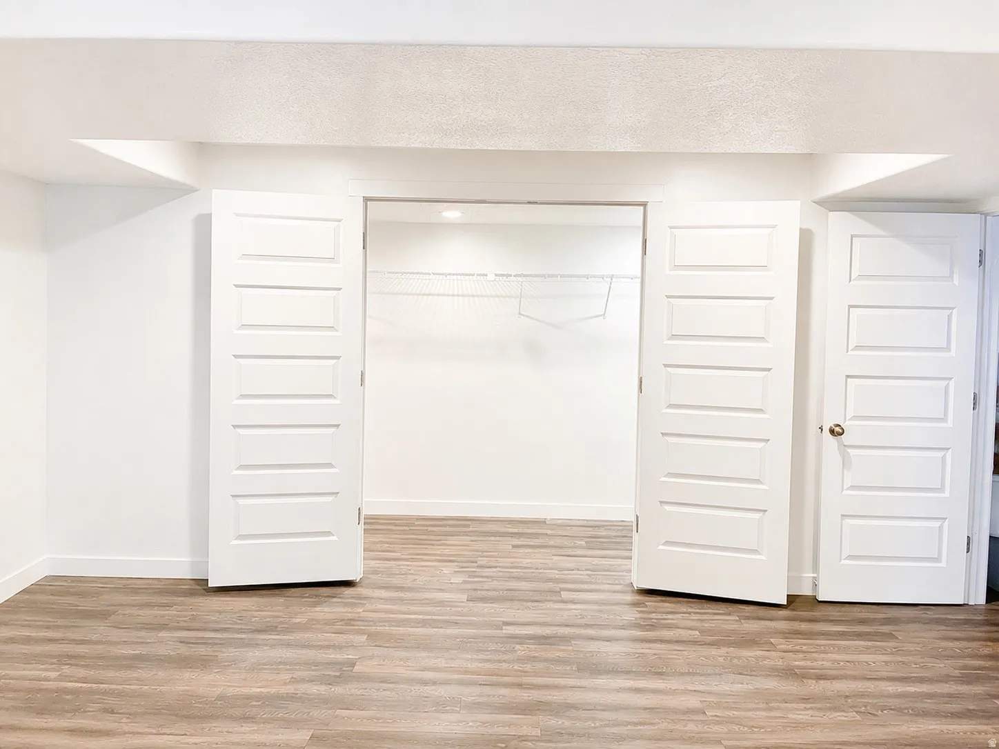 Spacious room featuring waterproof luxury vinyl plank flooring, white walls, and recessed lighting