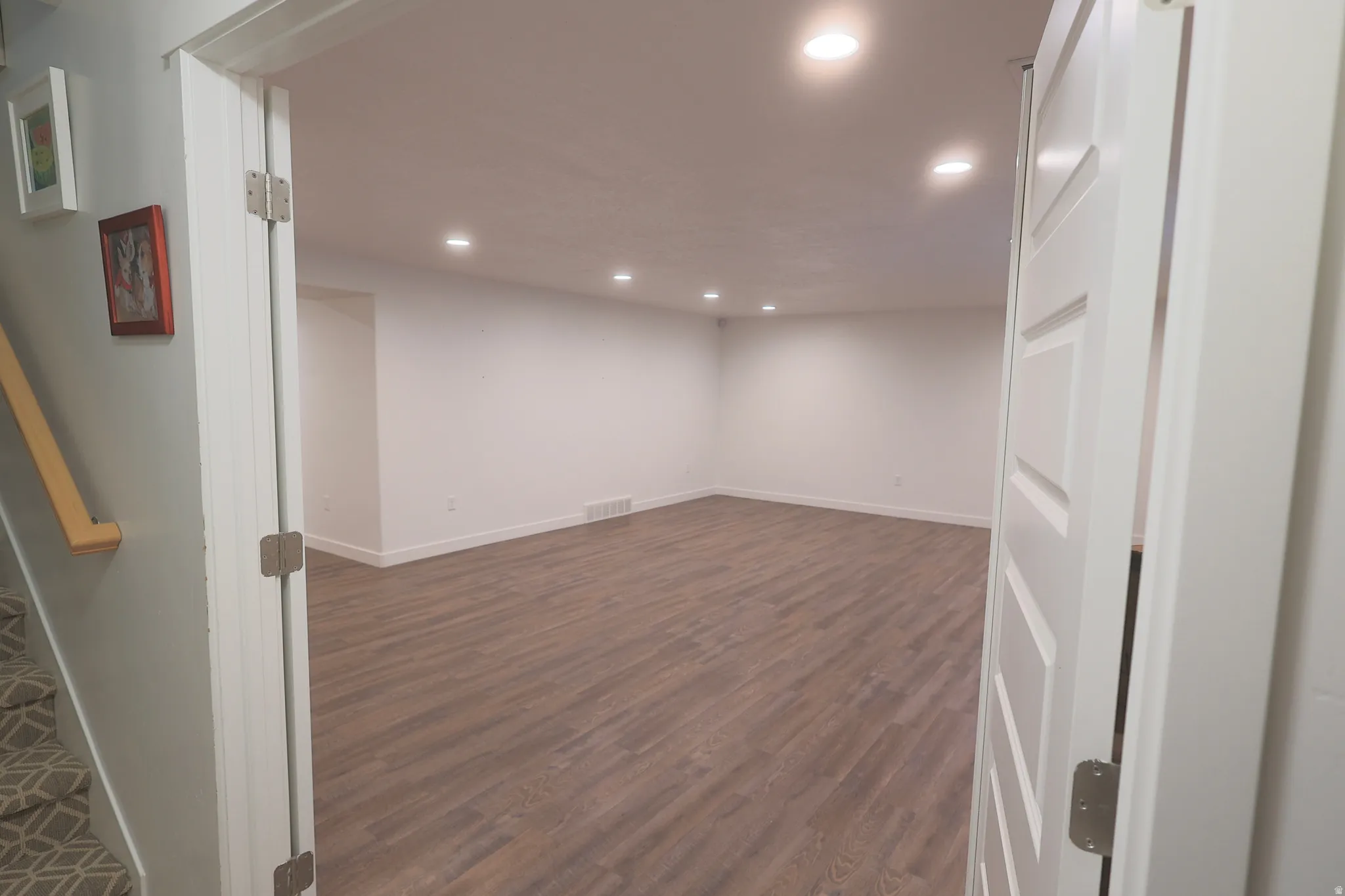 Spacious basement family room featuring waterproof luxury vinyl plank flooring, recessed lighting, white baseboards, and white walls