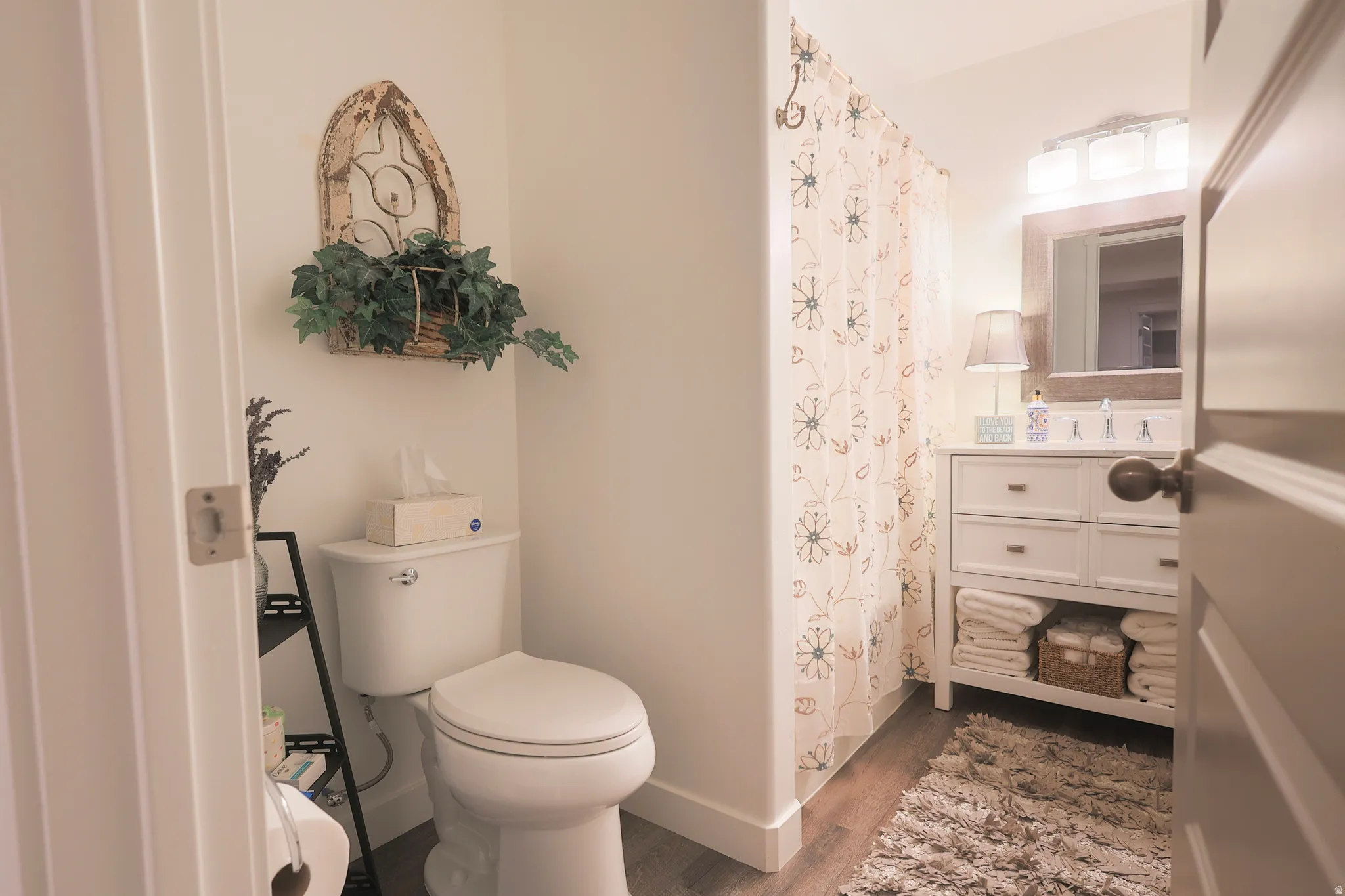 Bathroom with waterproof luxury vinyl plank flooring, a white vanity with integrated sink, full bathtub, and overhead lighting