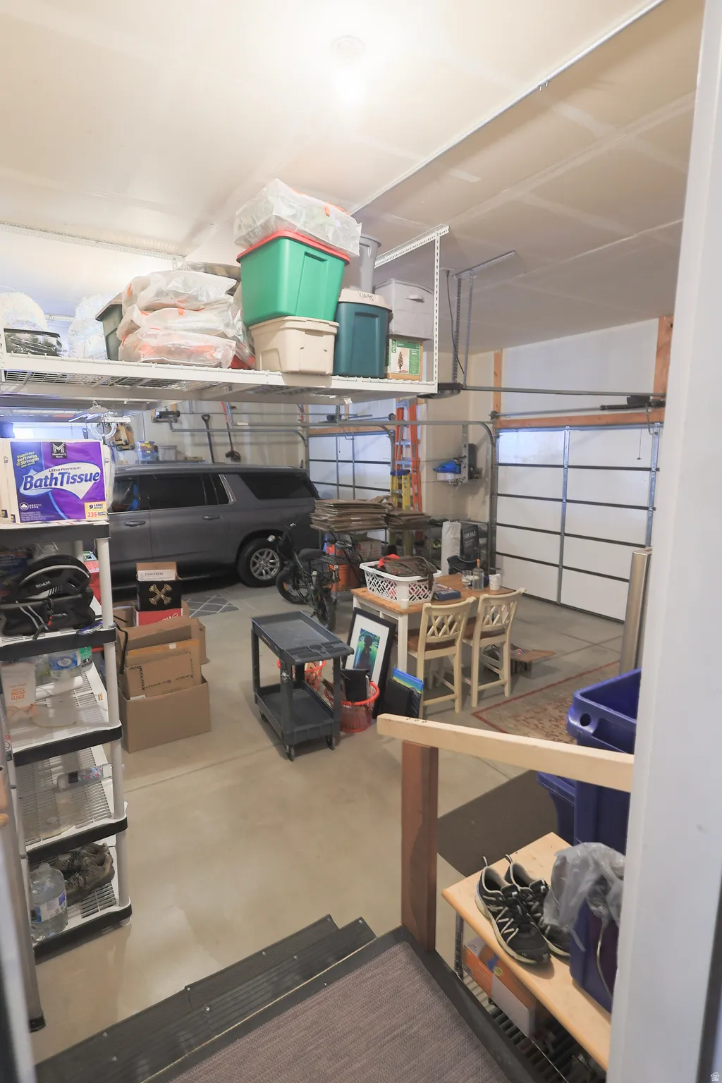 Spacious garage featuring a concrete floor, two overhead garage doors, and built-in overhead storage shelves