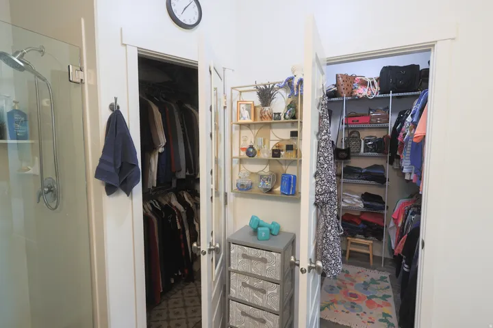 Two open master walk in closets featuring built-in shelving