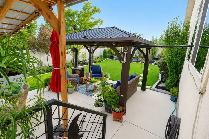 Expansive concrete patio featuring a dark wood gazebo with a metal roof and built-in lighting