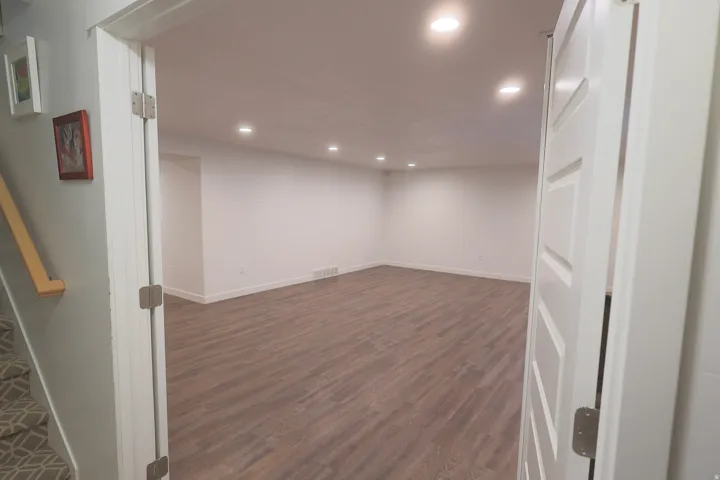 Spacious basement family room featuring waterproof luxury vinyl plank flooring, recessed lighting, white baseboards, and white walls
