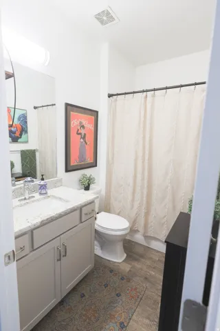 Full second Bathroom on first level featuring a light-toned vanity with a white countertop and integrated sink, a white toilet, and waterproof luxury vinyl plank flooring