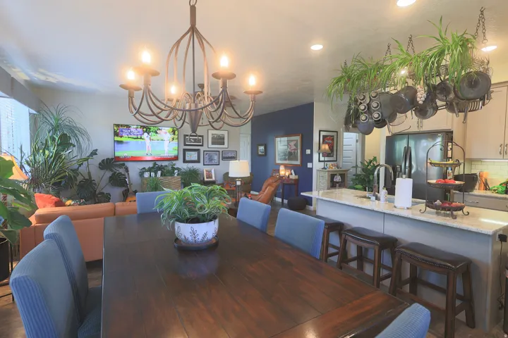 Open-concept living space featuring a wrought iron chandelier, kitchen island with seating and stainless steel refrigerator