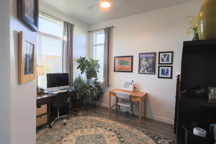 Bright bedroom with two windows featuring blinds, waterproof luxury vinyl plank flooring, a ceiling fan, and white walls