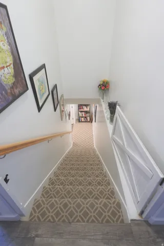 Staircase featuring a patterned carpet runner, safety wooden gate, and a wooden handrail