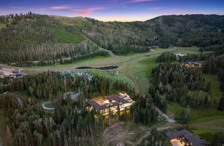 Sprawling mountain estate featuring extensive exterior lighting, multiple terraces, and a stone driveway
