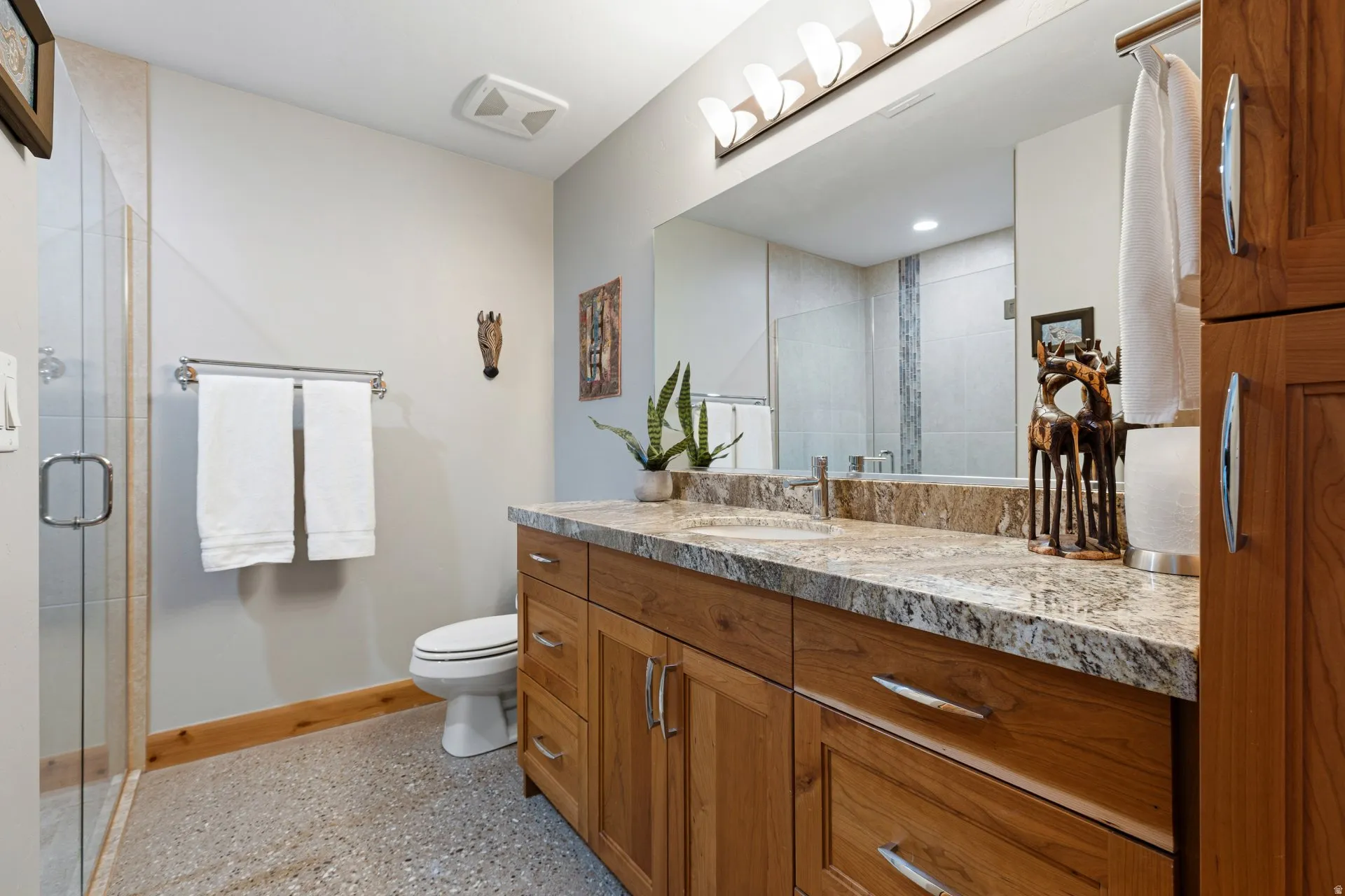 Bathroom featuring a large wood-finish vanity with a stone countertop, an integrated sink, and a full-width mirror