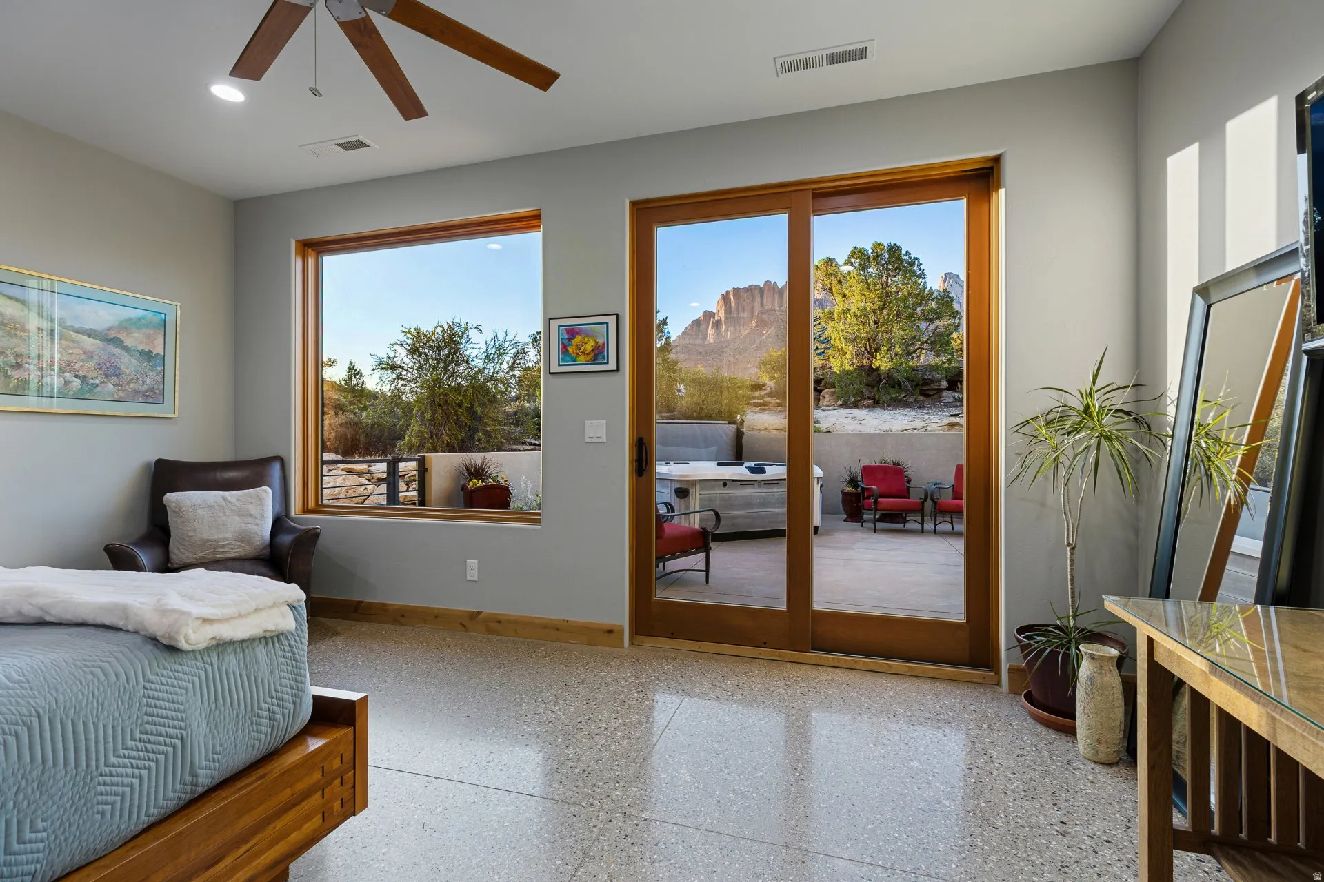 Spacious room featuring polished aggregate flooring, a five-blade ceiling fan with integrated lighting, and a large picture window
