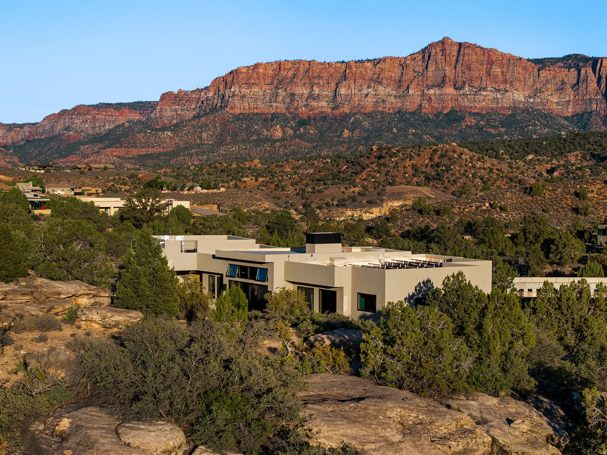 Wide view of the home set below the towering red rock cliffs of the Zion gateway.