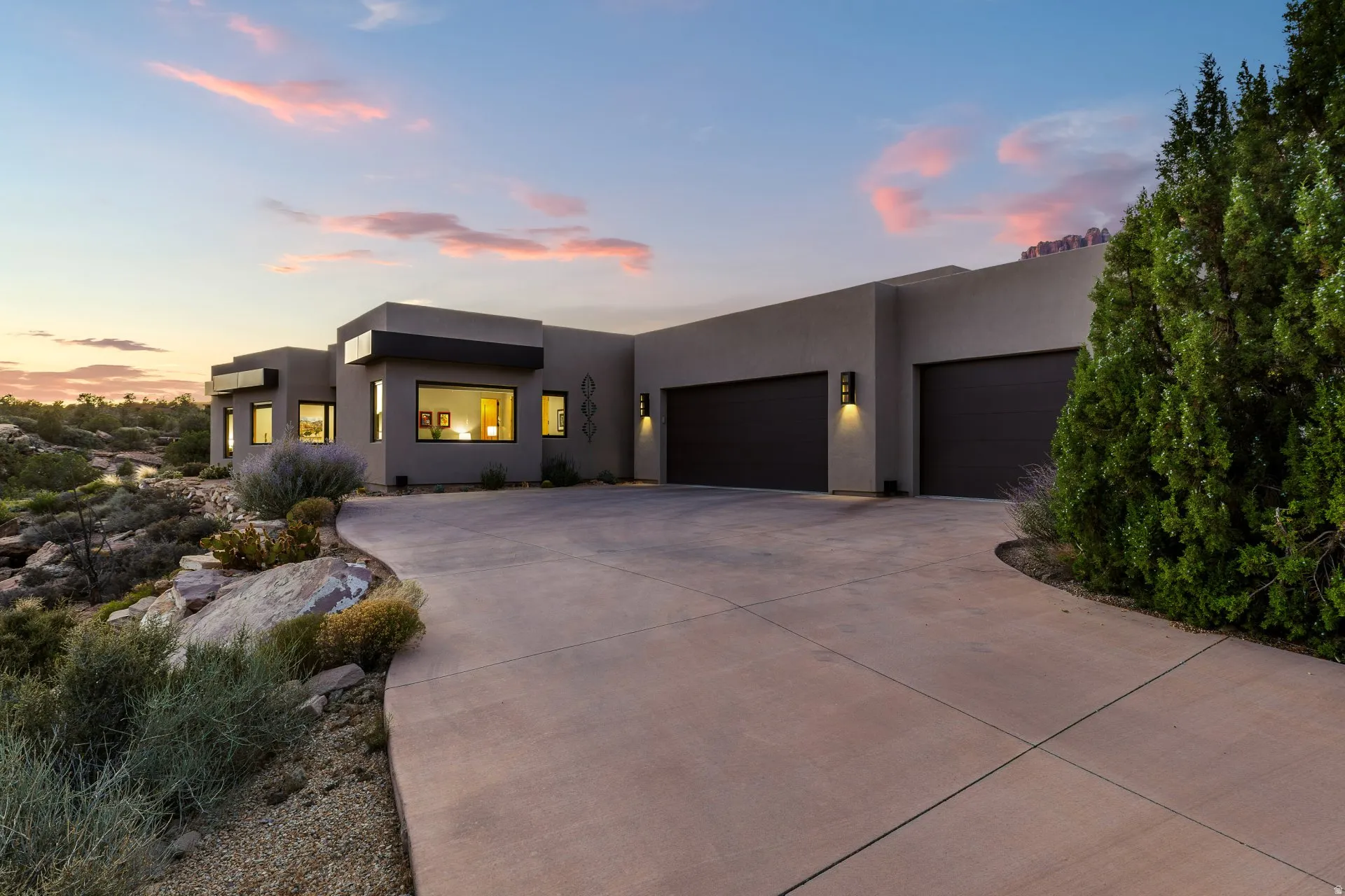 Contemporary stucco exterior featuring multiple dark-toned garage doors