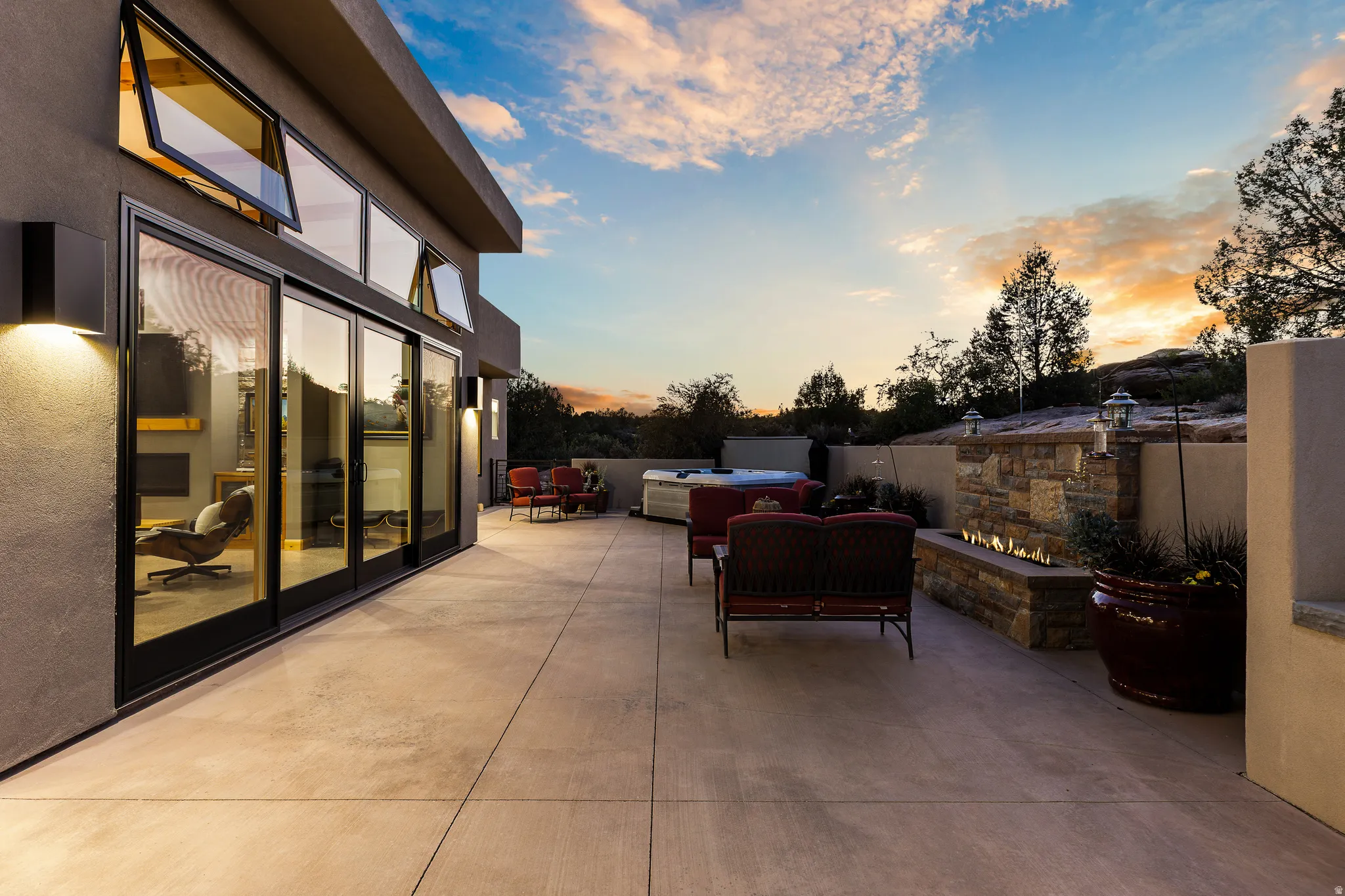 Rear patio at twilight showing the home's glass wall and covered outdoor living space.