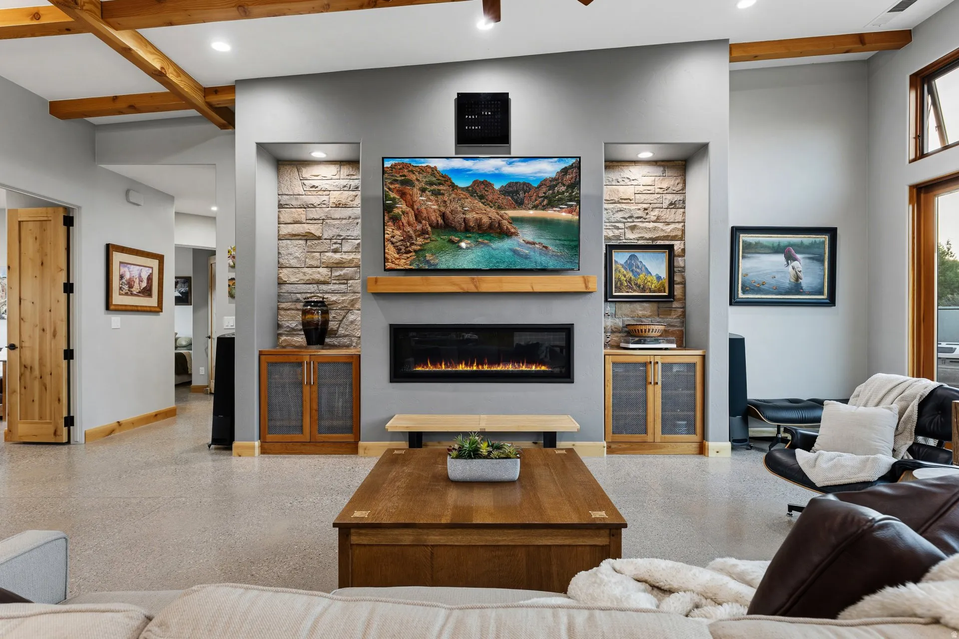 Living area featuring a floor-to-ceiling stone-faced media wall, integrated electric fireplace, and a wood-finish mantel