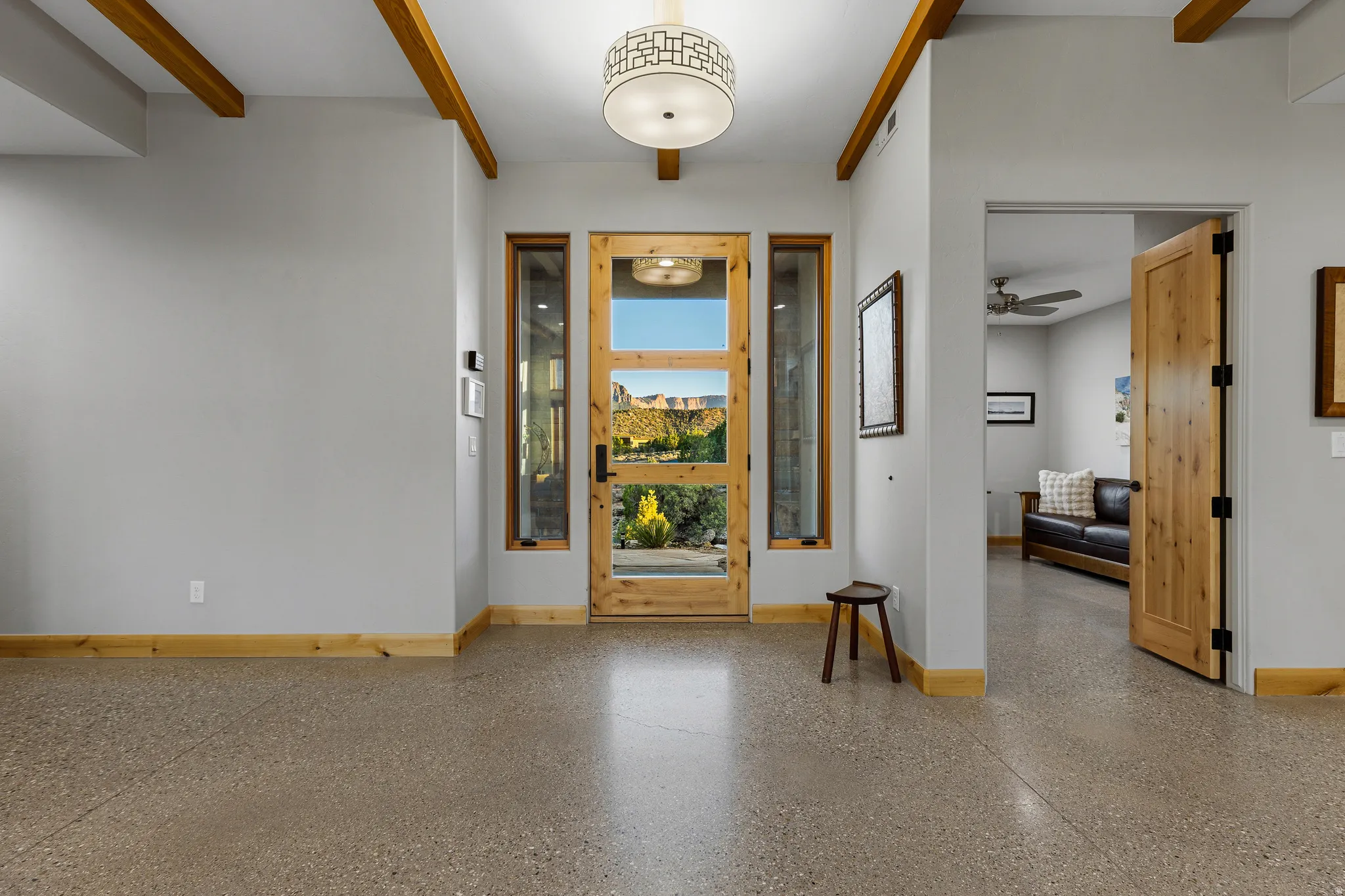 Interior entry with glass-paneled front door and polished concrete flooring leading into the main living space.