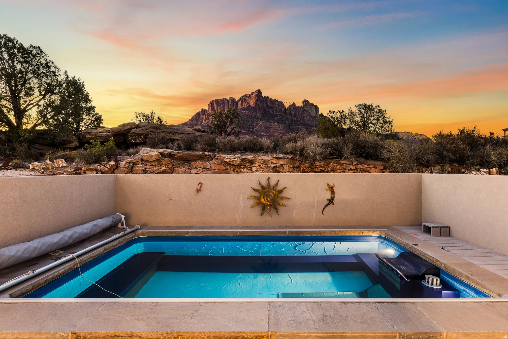 Outdoor inground pool with integrated steps, surrounded by light-colored coping and stucco walls