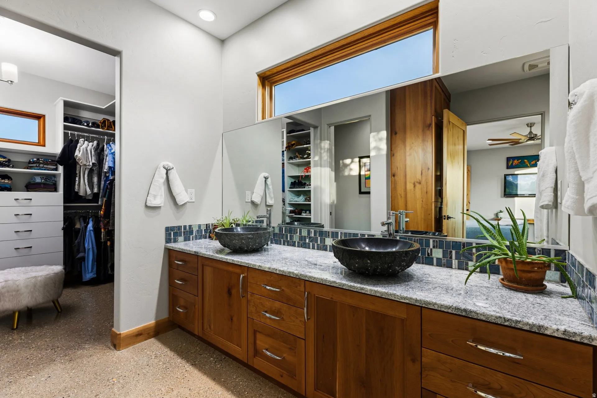 Dual vessel sinks set into a light-toned countertop with a mosaic tile backsplash