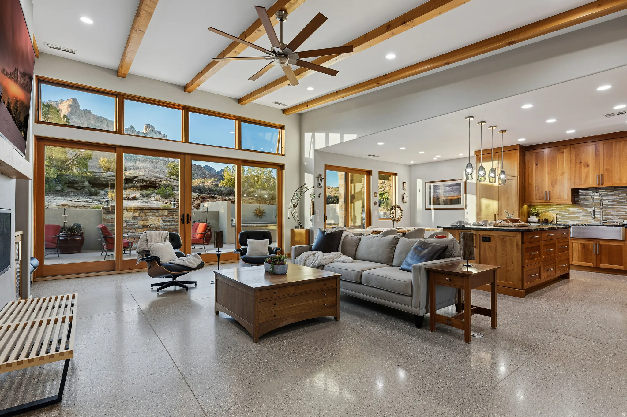 Great Room with 13-foot vaulted ceilings, polished concrete floors, and a wall of windows framing the surrounding landscape, opening directly to the kitchen.