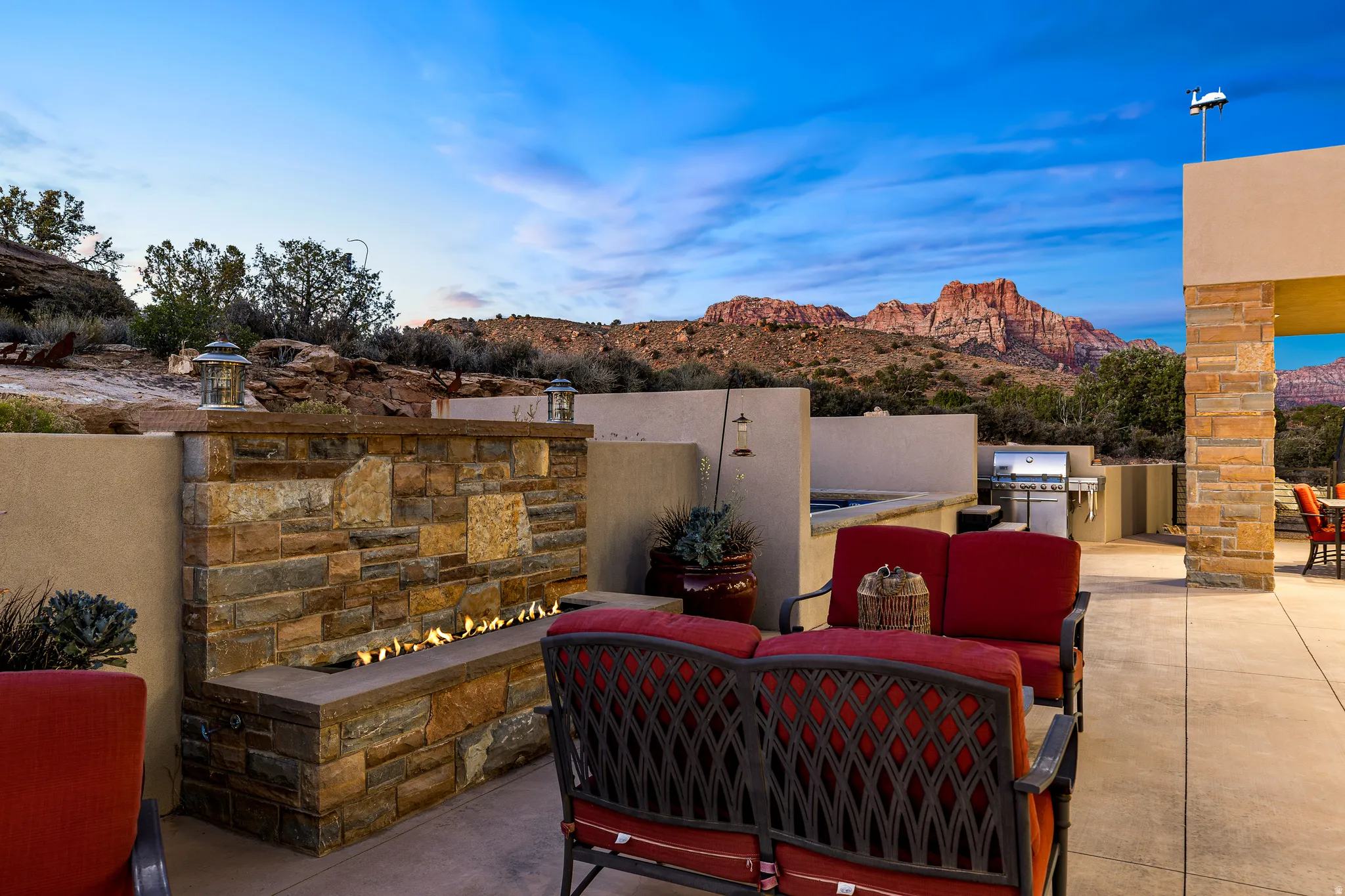 Outdoor patio featuring a linear stone fire pit, built-in BBQ grill, and a contrasting stone accent wall