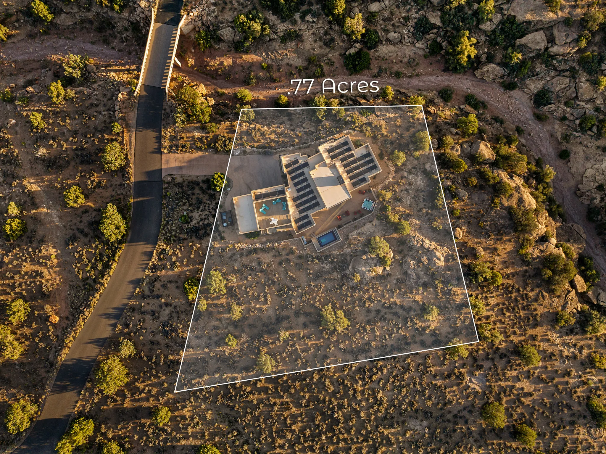77-acre desert property featuring a contemporary-style residence with multiple rooftop solar arrays, a swimming pool, and an additional outdoor water feature