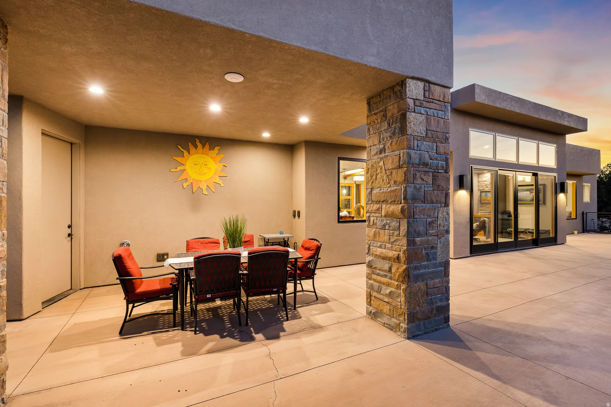 Expansive concrete patio area featuring a stone-clad column and recessed lighting