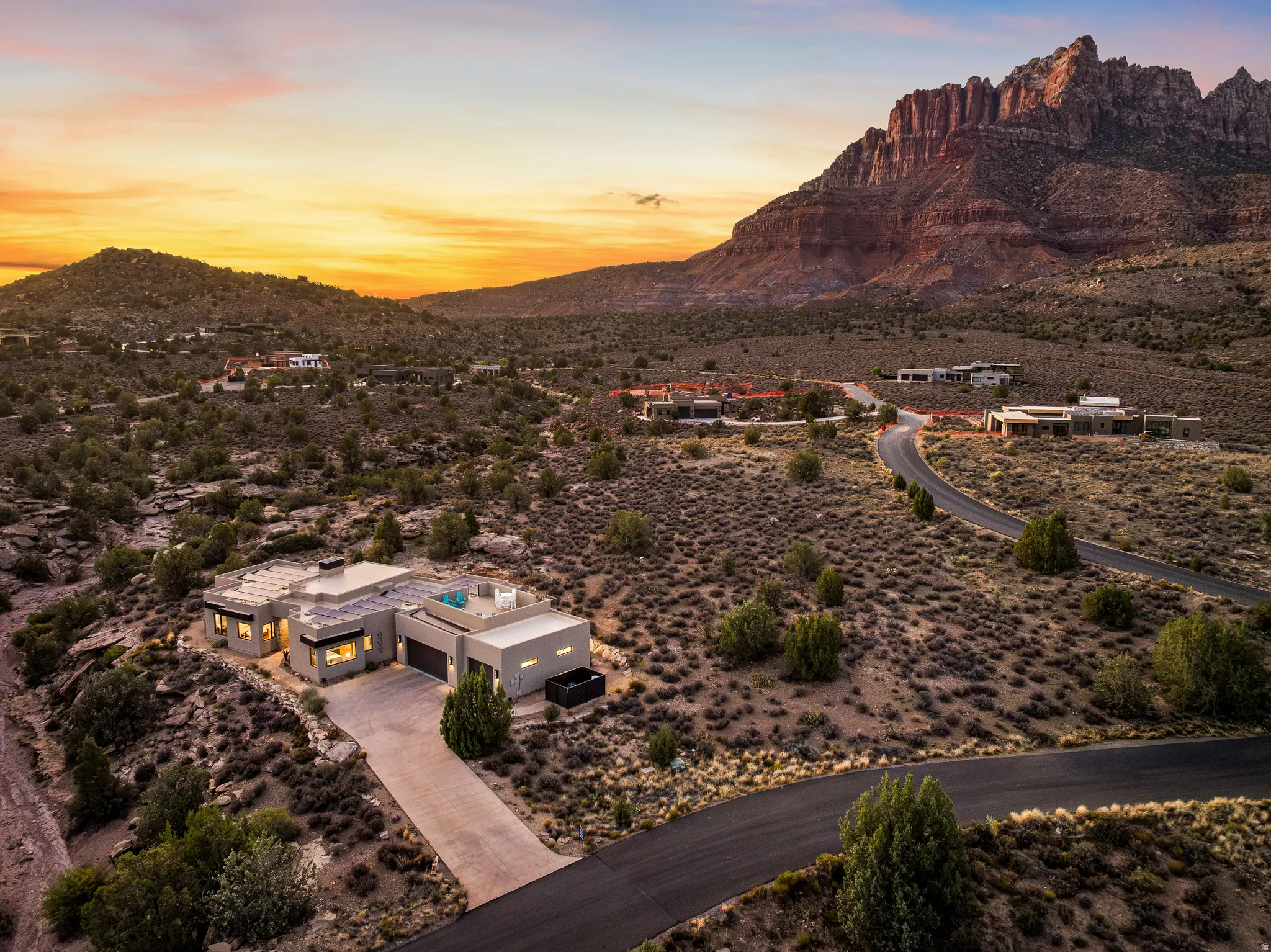 Modern desert architecture featuring a flat roofline, integrated solar panels, and a concrete driveway