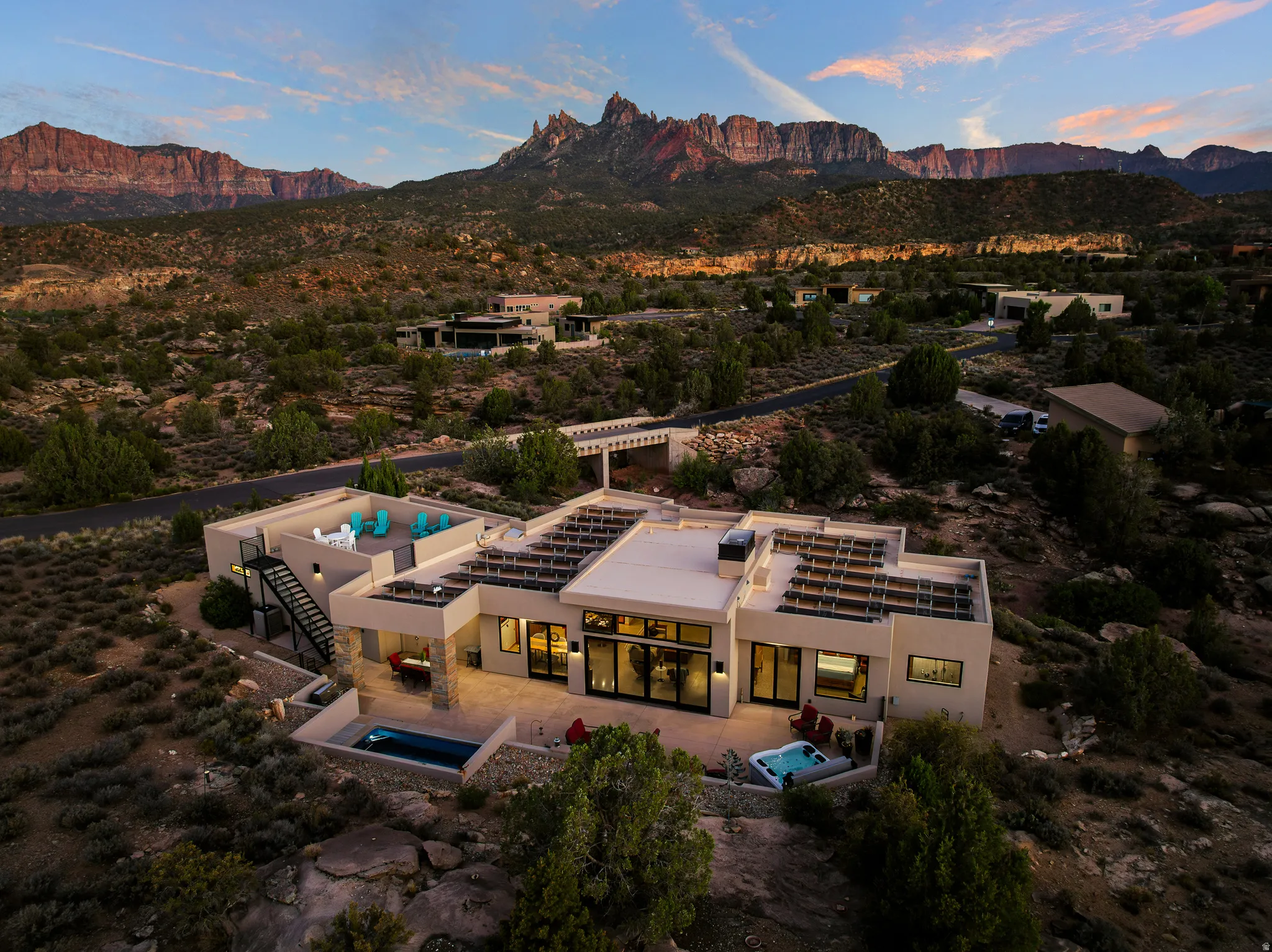 Aerial at dusk with the home lit and the surrounding Anasazi Plateau homesites visible.