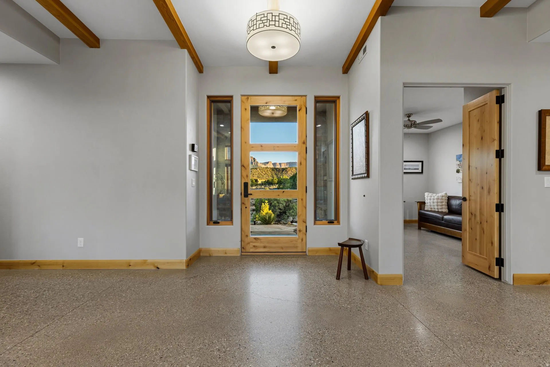 Entryway featuring a wood-frame glass panel door with sidelights, exposed wood ceiling beams, a decorative ceiling light fixture, and polished concrete flooring