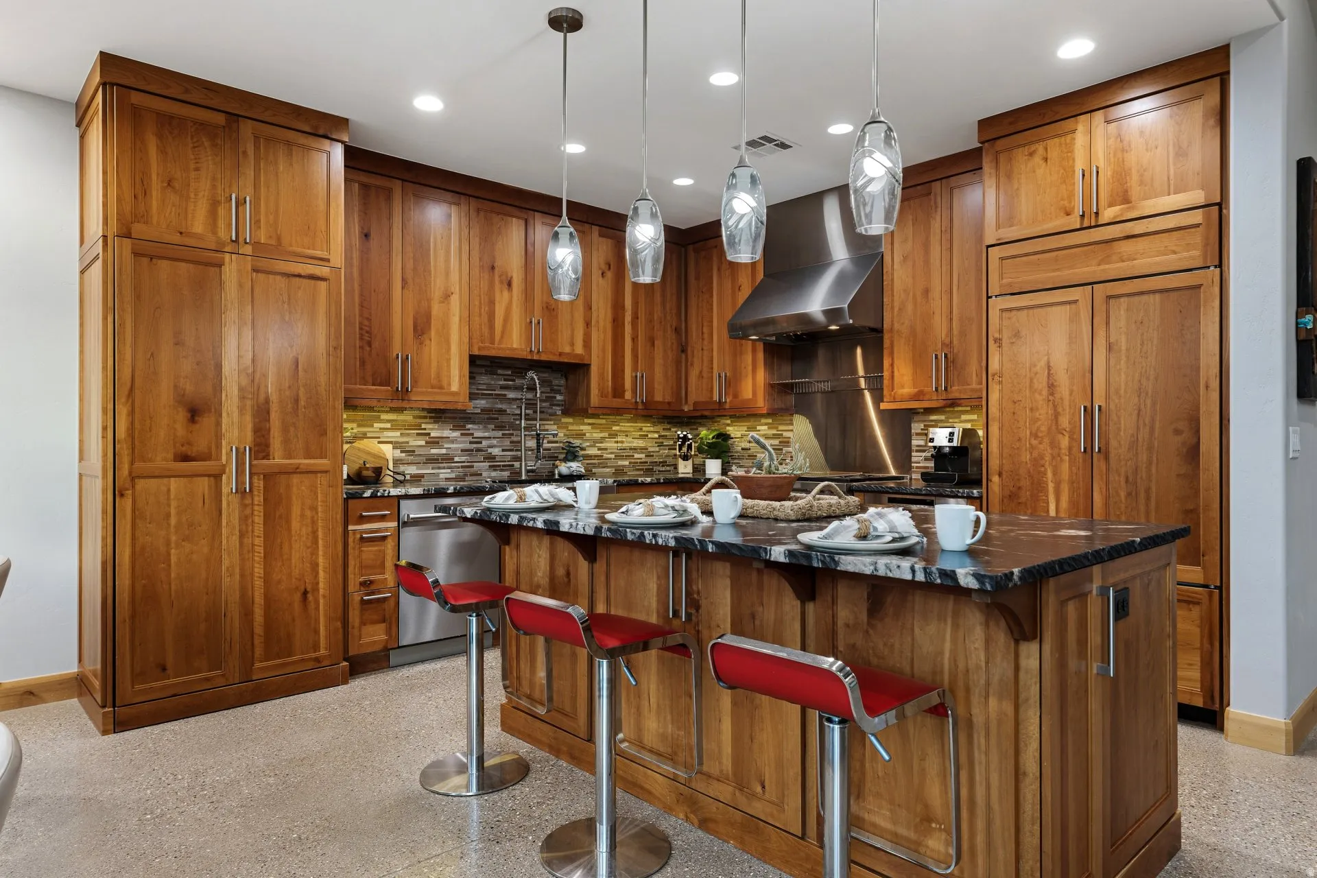 Kitchen featuring extensive wood cabinetry, a central island with a dark stone countertop, stainless steel appliances, and a mosaic tile backsplash