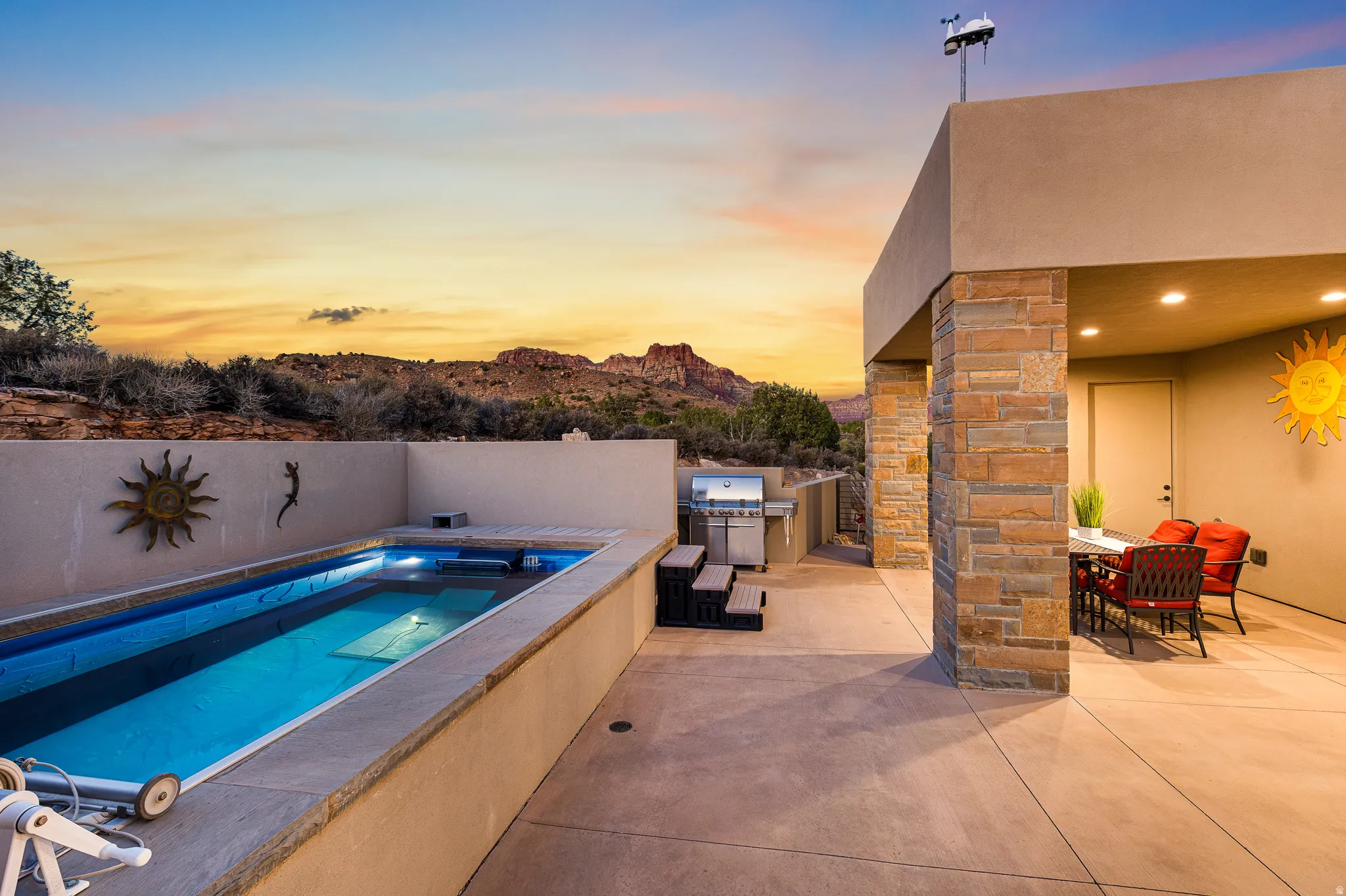 Private outdoor patio featuring a narrow swimming pool with integrated lighting, a built-in outdoor kitchen with a grill, and a covered dining area