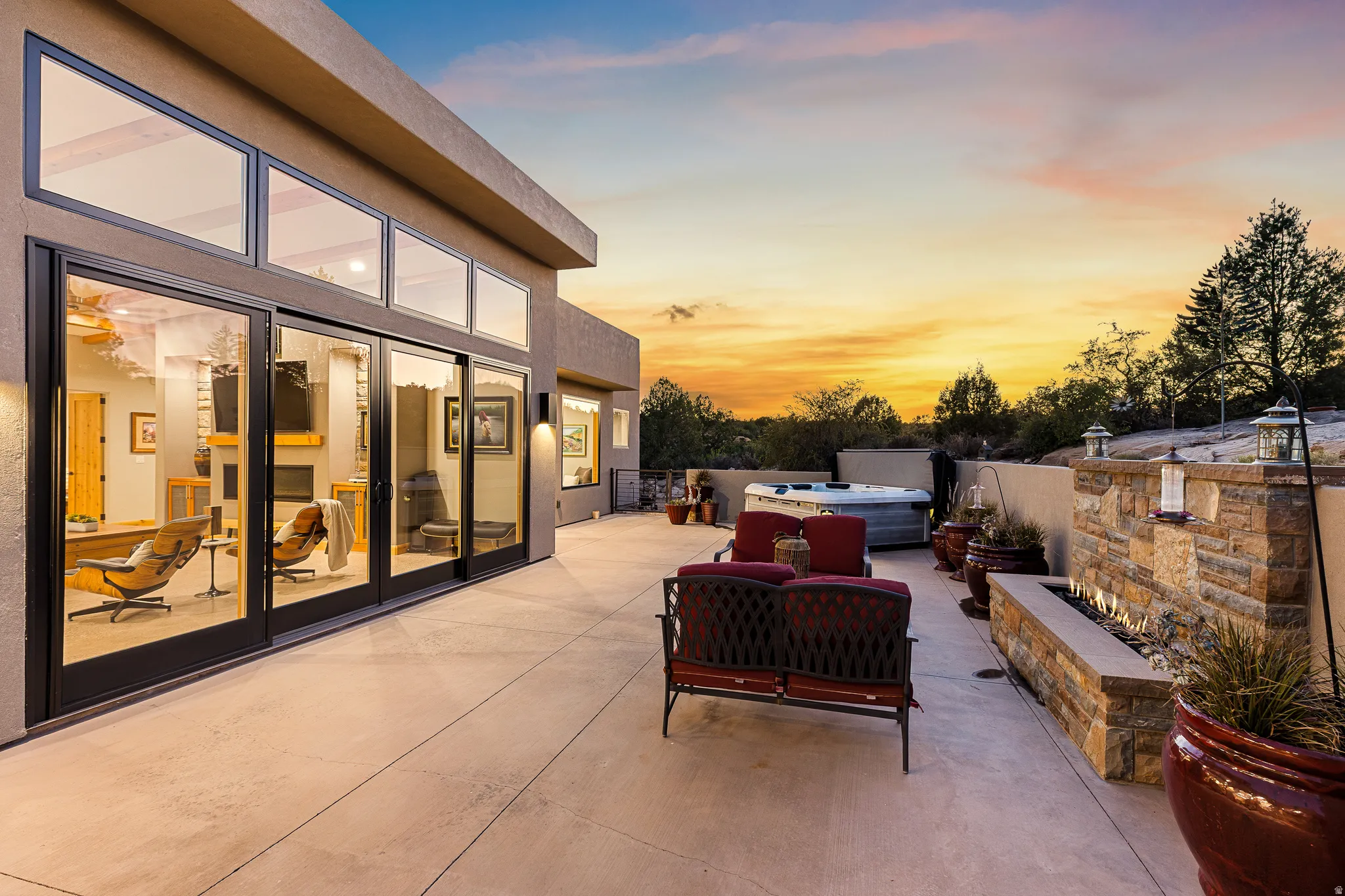 Expansive outdoor patio featuring a built-in stone fire pit, integrated spa, and exterior lighting