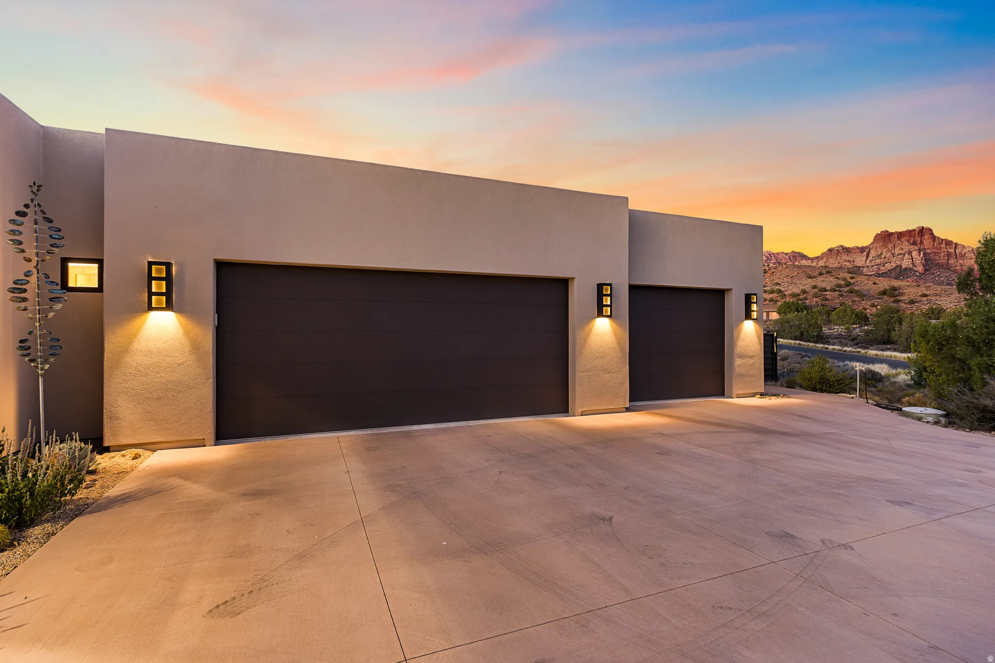 Modern exterior featuring two garage doors, contemporary wall sconces, and a concrete driveway
