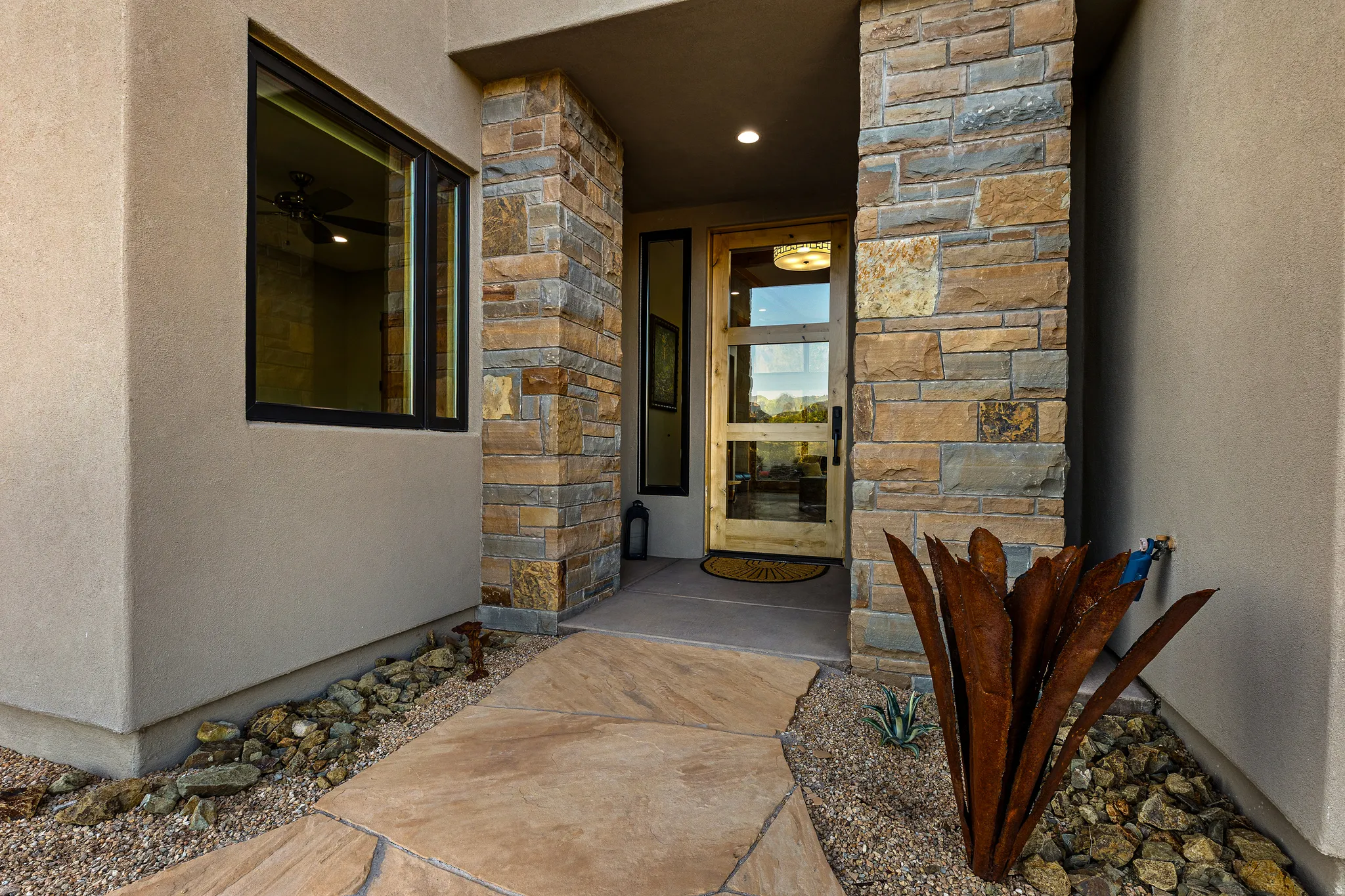 Covered front entry with stone accent wall and a metal desert sculpture detail.
