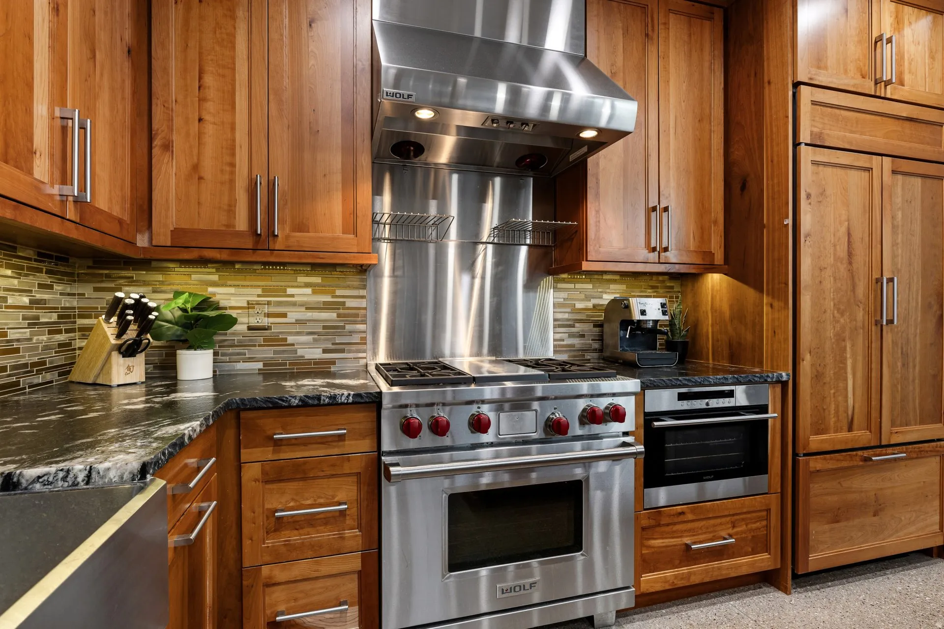 Gourmet kitchen featuring a stainless steel gas range with a matching professional-grade range hood, built-in wall oven, panel-front refrigerator, and custom wood cabinetry
