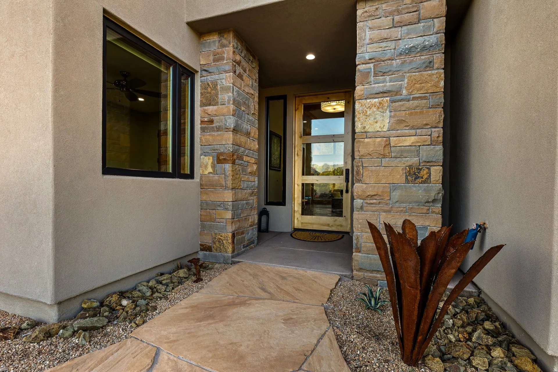 Entryway featuring a natural stone facade, stucco exterior, and a contemporary wood-paneled door with glass inserts