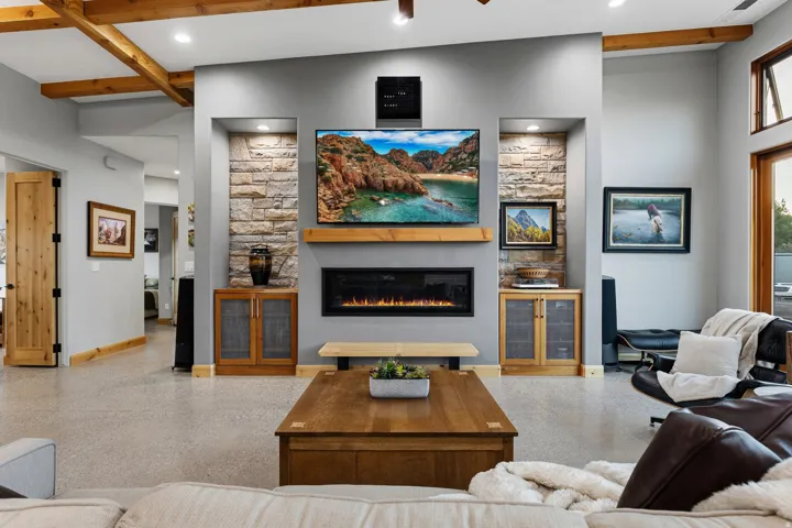 Living area featuring a floor-to-ceiling stone-faced media wall, integrated electric fireplace, and a wood-finish mantel