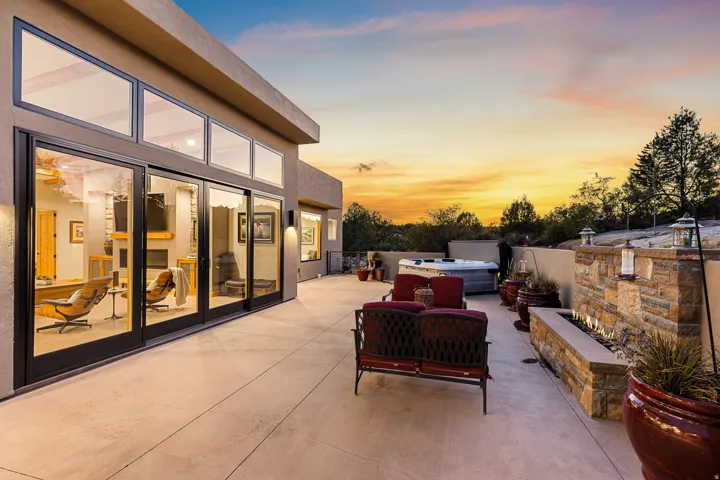 Expansive outdoor patio featuring a built-in stone fire pit, integrated spa, and exterior lighting