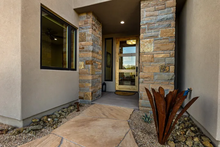 Entryway featuring a natural stone facade, stucco exterior, and a contemporary wood-paneled door with glass inserts